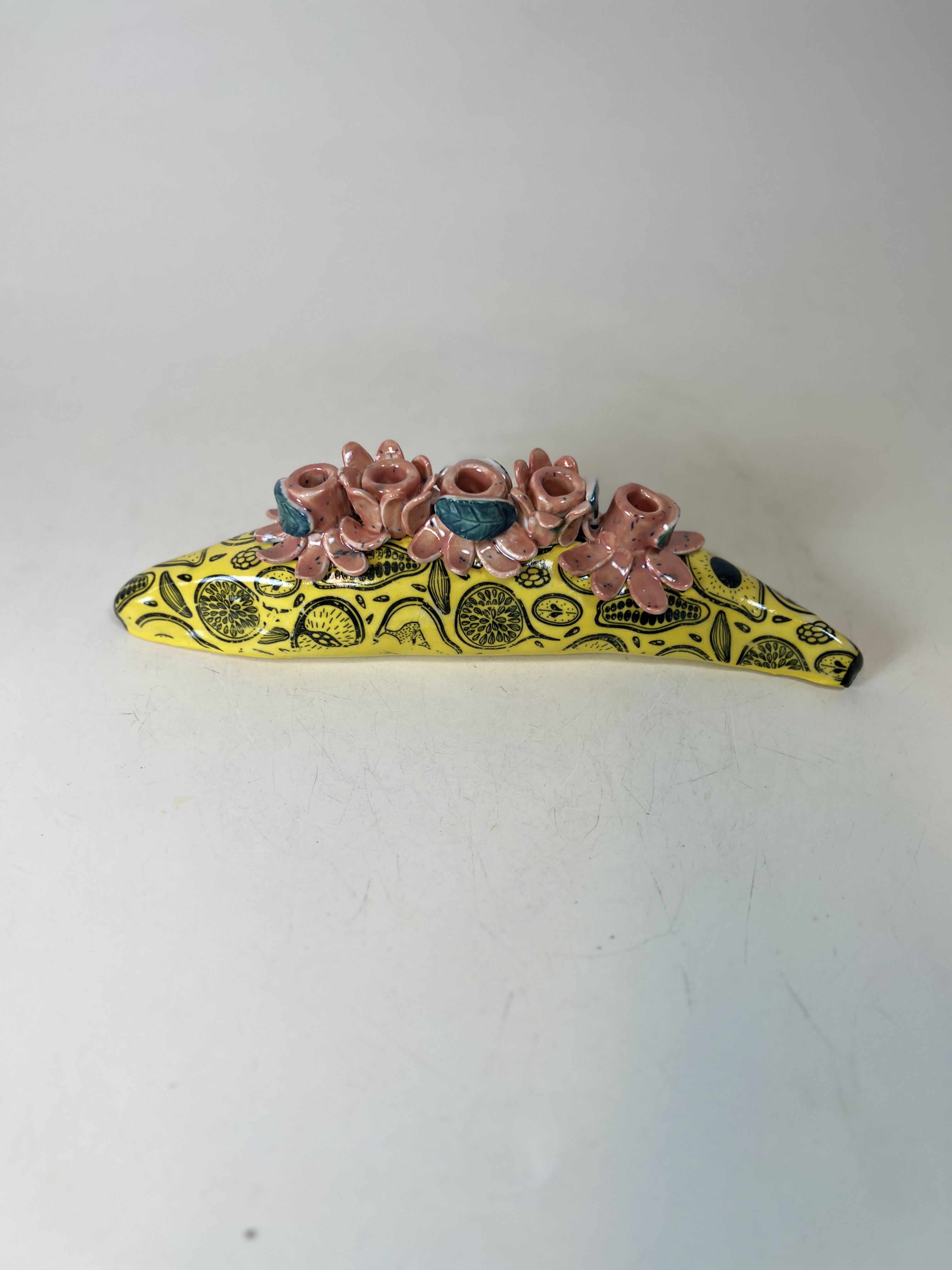Yellow citrus-patterned ceramic candelabra with pink sculptural rosebud holders